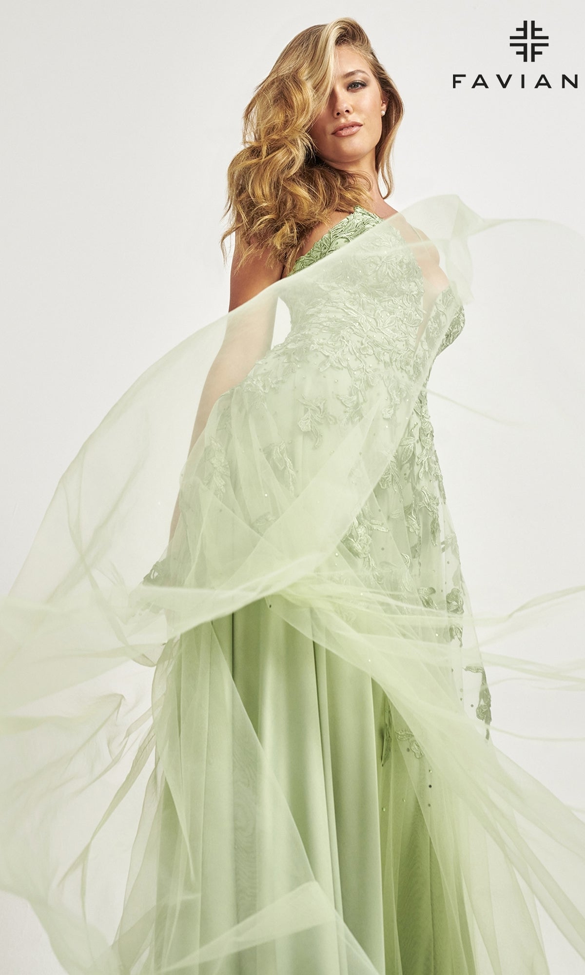 A woman in a light green Faviana Embroidered A-Line Long Prom Dress with 3-D flowers poses elegantly before a white background,